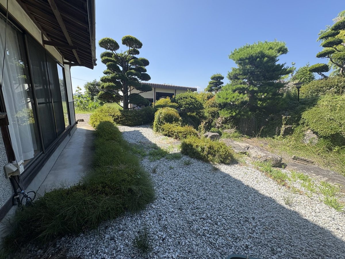 松本市梓川の庭園除草前：縁側沿いの玉砂利の通路に雑草が点在する状態