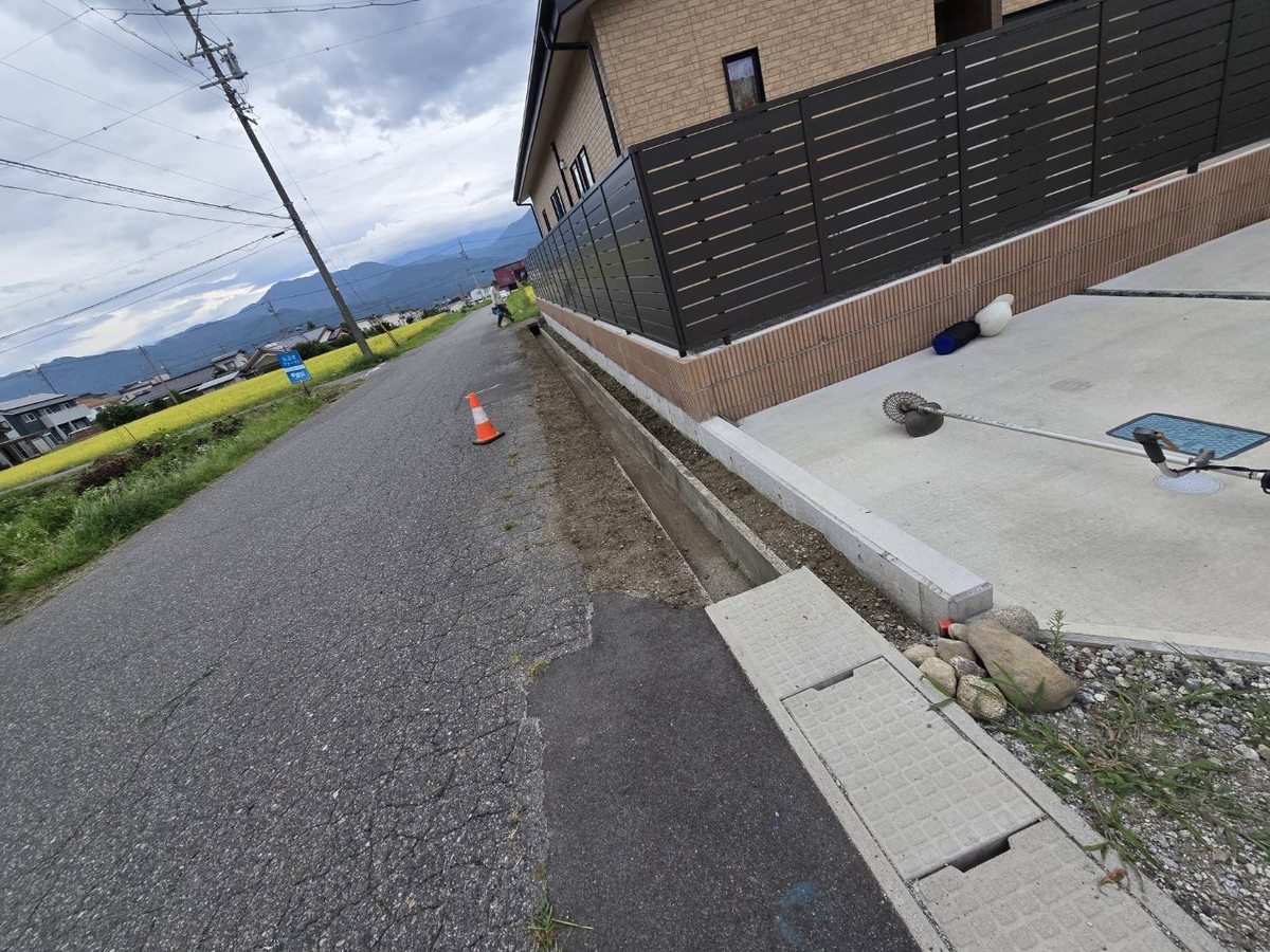 駒ヶ根市の道路縁の草刈り後:フェンス沿いの雑草が除去され縁石がすっきり見える状態