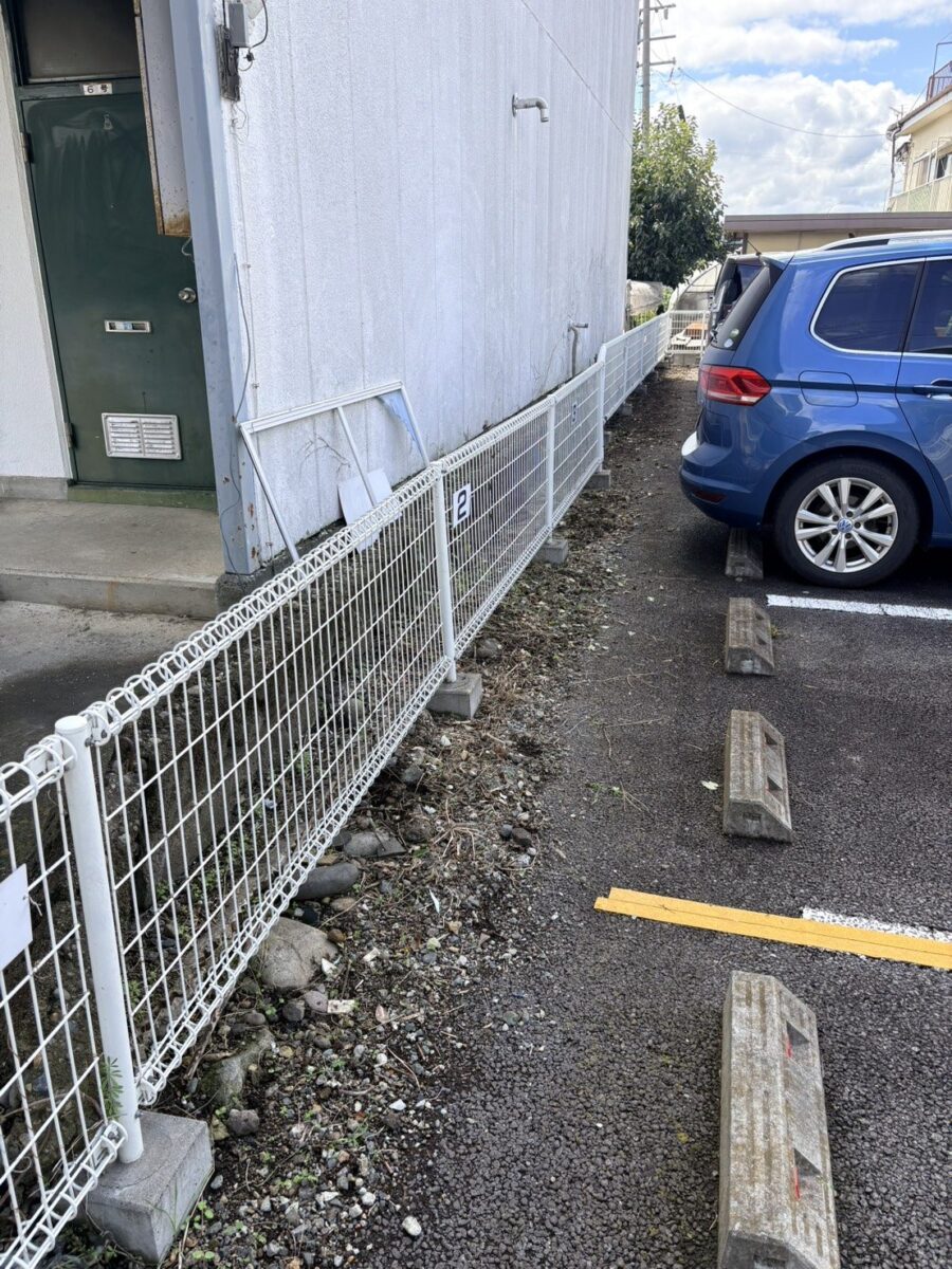 上田市のアパート駐車場の草むしり後：フェンス際がすっきり刈り込まれた通路