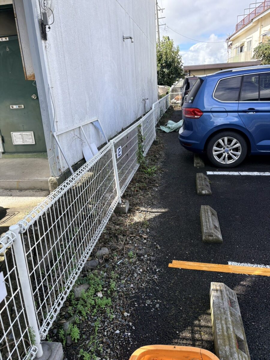 上田市のアパート駐車場の草むしり前：フェンス際に雑草が生えた通路